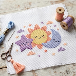 May include: A cross-stitch design featuring a smiling sun, moon, and star in yellow, blue, and purple. The design is on white fabric, with embroidery floss, scissors, and thread spools nearby. A cute, whimsical theme.
