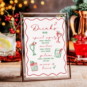 May include: A framed drinks menu with a red and white design. The menu lists various cocktails, including Aperol Spritz, Martini, and Paloma. Decorative illustrations of drinks are included. The background features festive holiday decorations.