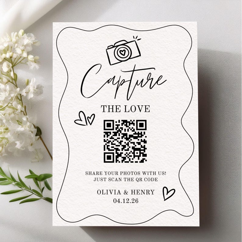May include: A white card with black script and a QR code. The words "Capture the Love" are above the code, with a camera icon. Below the code, it says "Share your photos with us! Just scan the QR code." The names "Olivia & Henry" and the date "04.12.26" are at the bottom.