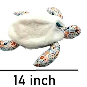 Może przedstawiać: Pluszowy żółw, o długości około 35,5 cm, z puszystym białym korpusem oraz wzorzystymi płetwami i głową. Płetwy i głowa mają kolorowy kwiatowy wzór z odcieniami niebieskiego, pomarańczowego i brązowego. Zabawka ma przypominać żółwia morskiego.