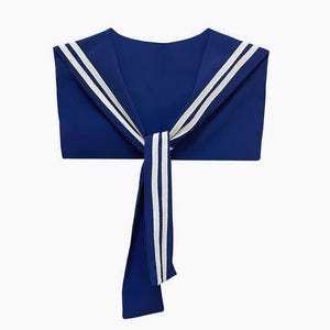 Könnte beinhalten: Ein marineblauer Matrosenkragen mit zwei weißen Streifen. Der Kragen ist vorne mit einer passenden marineblauen Krawatte gebunden, die ebenfalls zwei weiße Streifen aufweist. Ein klassisches nautisches Accessoire.