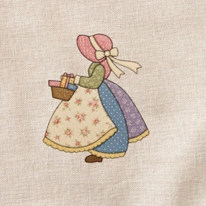 Może przedstawiać: Aplikacja z tkaniny przedstawiająca kobietę w czepku i sukni, niosącą kosz z prezentami. Suknia kobiety to patchwork z kwiatowych, w kropki i gładkich tkanin w pastelowych kolorach. Czepek jest różowy z białą wstążką.