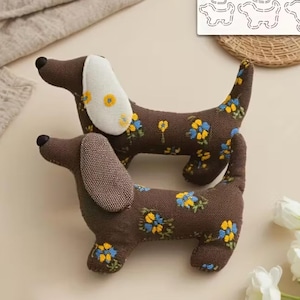 Könnte beinhalten: Zwei braune Dackel-Stofftiere mit blauen und gelben Blumenmustern. Ein Hund hat ein weißes Ohr mit gelben Blumenakzenten. Der andere Hund hat ein braunes Ohr. Die Hunde sind aus Stoff und haben schwarze Nasen.