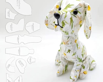 以下が含まれることがあります： 白、黄色、緑の花柄の生地で作られた犬のおもちゃ。犬は黒い目と黒い鼻をしています。犬の左側には縫製パターンが見えます。