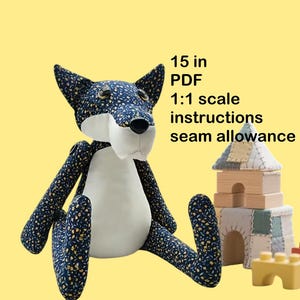 May include: A plush fox toy, approximately 15 inches tall, with a white belly and face, and navy blue fabric patterned with small yellow flowers. The fox is sitting with its legs extended. Text on the image reads "15 in PDF 1:1 scale instructions seam allowance."