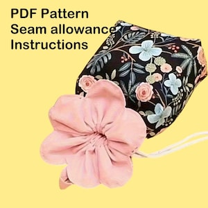 Puede incluir: Una bolsa de tela con estampado floral y cordón, junto con un gran accesorio en forma de flor rosa. La bolsa tiene un fondo negro con patrones florales blancos, rosas y azules. El texto en la imagen dice: PDF Pattern, Seam allowance, Instructions.