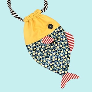 Könnte beinhalten: Ein skurriler Kordelzugbeutel in Form eines Fisches. Die Tasche hat einen gelben Kopf, einen Körper mit Blumenmuster und rot-weiß gestreifte Flossen und Schwanz. Ein schwarz-weißes Seil dient als Kordelzug.