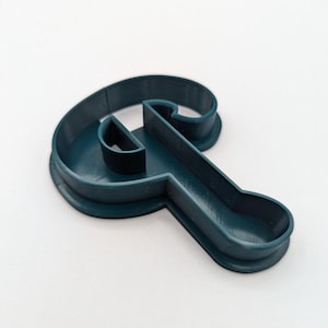 May include: A teal blue plastic cookie cutter shaped like the letter Q.