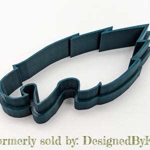 May include: A teal blue plastic cookie cutter shaped like an eagle's head. The cutter has a detailed design with a sharp beak and a wing.