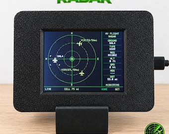 May include: A black rectangular flight radar display device with a textured frame and a stand. The screen shows a green circular radar interface with airplane icons, directional markers, and text including MY FLIGHT RADAR, DAL4, A339, and N4100Z.