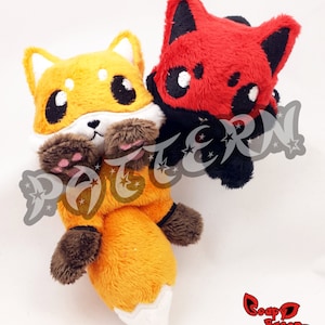 May include: Two plush fox toys, one orange and brown with a white tipped tail, the other red with black accents. The orange fox is sitting with its paws in front of it, while the red fox is standing behind it with its head tilted to the side.