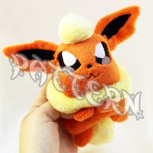 May include: Orange and black plush toy with a yellow collar. The toy has a white tuft on its head and black eyes.