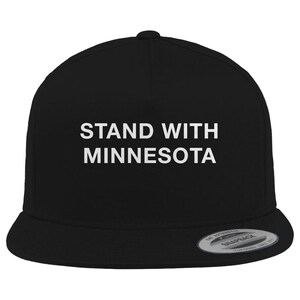 May include: Black snapback cap featuring the white text "STAND WITH MINNESOTA". The cap has a flat peak and a snap closure at the rear. A classic style, suitable for everyday wear.