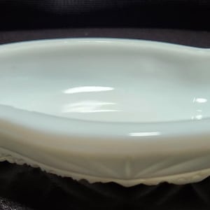 Puede incluir: Un plato blanco en forma de corazón con un borde festoneado. El plato tiene una superficie lisa y brillante y un interior poco profundo. El plato está hecho de un material sólido y opaco.