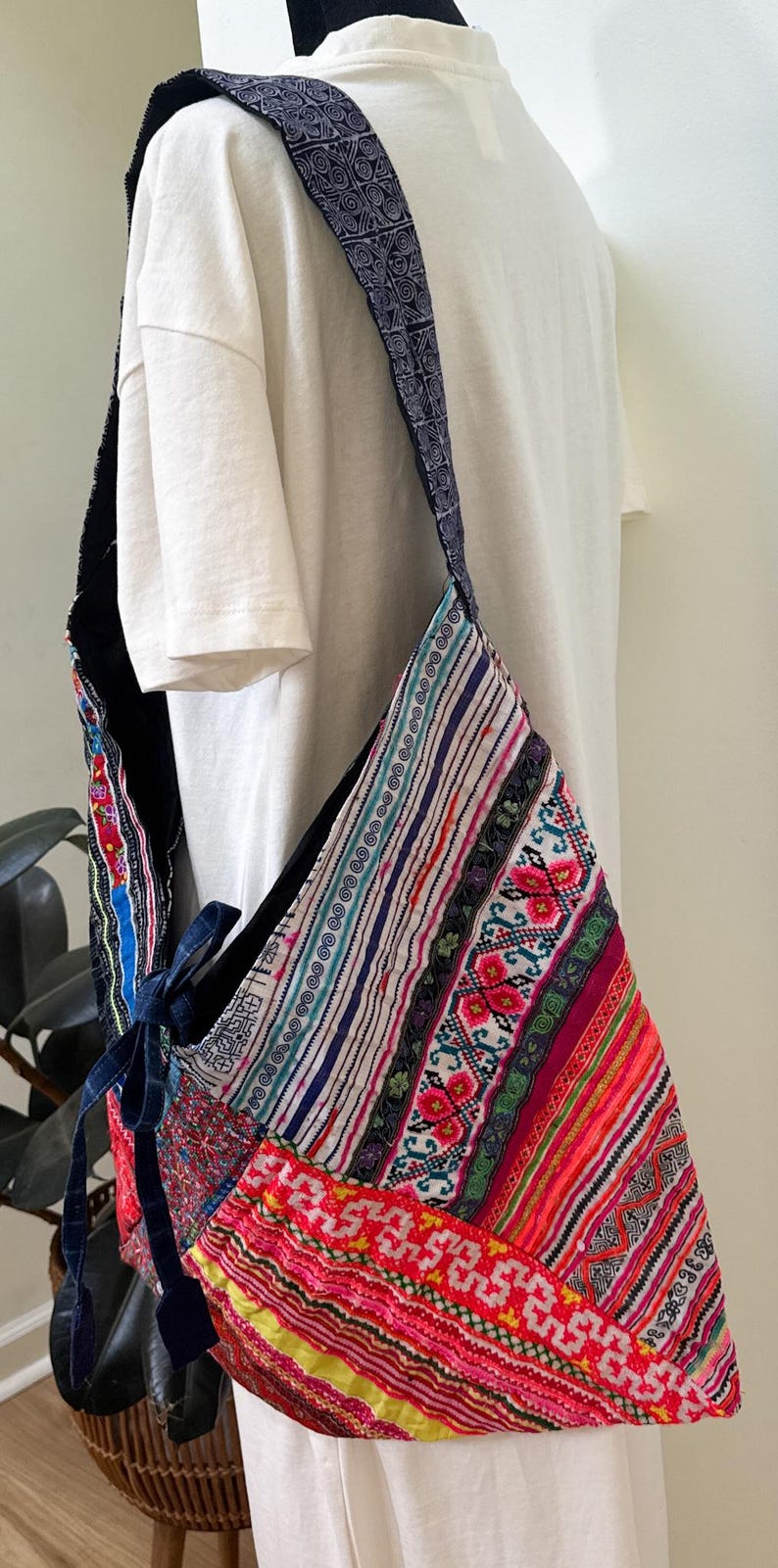 Puede incluir: Un bolso de hombro de patchwork colorido con una correa estampada. El bolso presenta una variedad de telas vibrantes en rojo, rosa, azul y verde, con dise&ntilde;os bordados y a rayas. La correa es azul oscuro con un patr&oacute;n repetitivo.