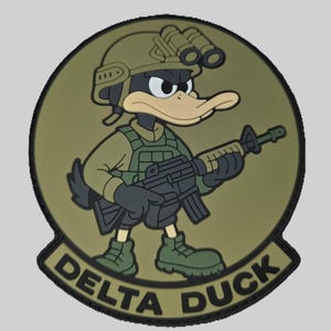Può includere: Una toppa circolare con un'anatra dei cartoni animati in tenuta militare, che tiene un fucile. L'anatra indossa un elmetto con visore notturno e un giubbotto tattico. Il testo "DELTA DUCK" è visualizzato in grassetto in basso.