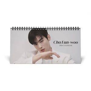 May include: A desk calendar with a spiral binding, featuring a portrait of Cha Eun-woo. The calendar has a white background and the text "Cha Eun-woo 2026 Calendar" is printed on the front.