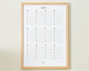 Puede incluir: Un calendario anual enmarcado de 2025 con un marco de madera clara. El calendario tiene un fondo blanco con el año 2025 en la parte superior. Cada mes está representado con una columna vertical de líneas. La esquina inferior derecha tiene las letras "SE" en un círculo.