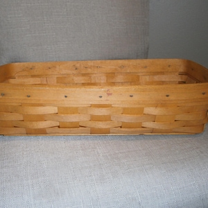 May include: A rectangular woven wood basket with a light brown finish. The basket features a flat base and vertical sides constructed from interwoven wooden strips, secured with small metal nails along the top rim for structural integrity.
