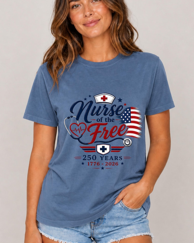 May include: Blue t-shirt with a graphic that reads "Nurse of the Free" in a patriotic design. The design includes a nurse's cap, stethoscope, and the American flag. The text "250 Years 1776-2026" is also included.
