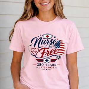 May include: A light pink t-shirt with the text "Nurse of the Free" in navy blue and red, with a stethoscope and American flag design. The shirt also features the text "250 Years 1776-2026".