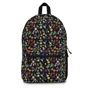 May include: A black backpack featuring a repeating pattern of various colorful birds, green fern leaves, and small flowers. The bag includes a large main compartment, a smaller front zippered pocket, a top handle, and a black mesh side pocket.