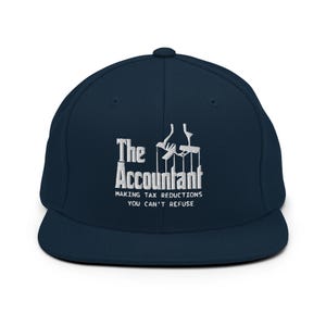 Può includere: Cappellino da baseball blu navy con visiera piatta, con testo ricamato bianco: "The Accountant" e "MAKING TAX REDUCTIONS YOU CAN'T REFUSE." Il design include una grafica di burattinaio. Un accessorio per contabili.