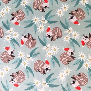 May include: A teal fabric with a repeating pattern of brown wombats wearing red Santa hats and white flowers.