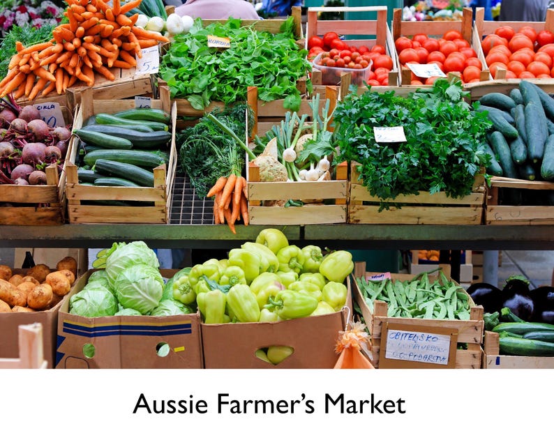 Op de afbeelding: Aussie Farmer's Market met verse producten. Houten kisten bevatten wortelen, bieten, komkommers, tomaten, groene paprika's en meer. De afbeelding toont een kleurrijke marktstand.