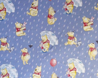 May include: A repeating pattern on a light blue background featuring the cartoon character Winnie the Pooh in various poses. The illustrations include Winnie the Pooh with a red balloon, holding an umbrella, and with Piglet. White rain drops and bees are also present.