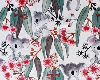 May include: A white fabric featuring a repeating pattern of gray koala bears, eucalyptus leaves, and red flowers. The koalas are depicted in various poses, surrounded by green and brown leaves and vibrant red blossoms.