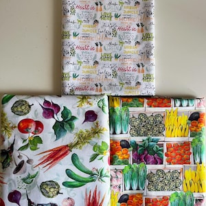 Op de afbeelding: Drie stukken stof met verschillende patronen. E&eacute;n stuk heeft de tekst "Heart is Home", "Green Vibes" en "Urban Jungle". De tweede heeft aquarel illustraties van groenten. De derde heeft illustraties van groenten in houten kisten.