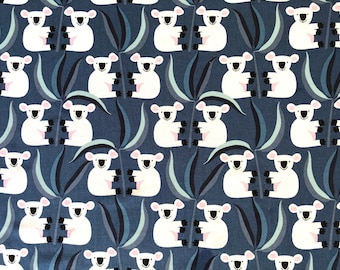 May include: A repeating pattern of white koala bears with pink accents and black features on a navy blue background. The koalas are interspersed with stylized green and blue leaf shapes, creating a playful and whimsical design.