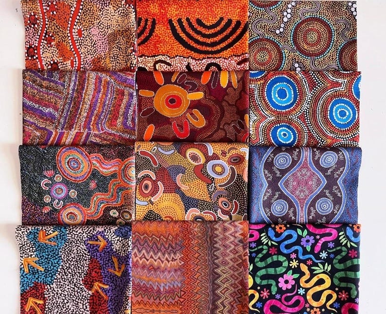 K&ouml;nnte beinhalten: Eine Sammlung farbenfroher Stoffquadrate mit Aboriginal-Dot-Art-Designs. Die Muster umfassen Kreise, Linien und abstrakte Formen in Rot-, Orange-, Blau- und Schwarzt&ouml;nen. Die Stoffquadrate sind in einem Raster angeordnet.