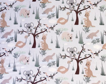 May include: A light gray fabric featuring a repeating pattern of Australian animals and plants. The design includes kangaroos, koalas, emus, platypuses, kookaburras, and wombat illustrations, along with stylized trees and grass.
