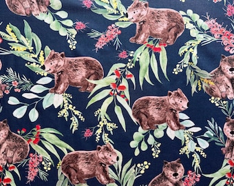 May include: Dark blue fabric featuring a repeating pattern of brown wombat illustrations amidst green leaves, yellow accents, and red flowers. The wombat illustrations are detailed and have a friendly appearance. The overall design has a whimsical, nature-inspired theme.