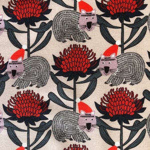 May include: A beige fabric with a repeating pattern of red and black flowers, gray and white wombats wearing red Santa hats, and dark green leaves.