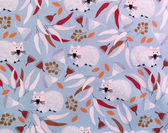 May include: A light blue fabric featuring a repeating pattern of white wombats, eucalyptus leaves, and seed pods. The leaves are in shades of white, brown, and red, with orange accents. The wombats have black whiskers and eyes.