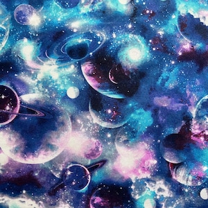 May include: A fabric design depicting a cosmic scene with planets, galaxies, and stars. The colour palette includes shades of blue, purple, and pink, creating a dreamy, celestial aesthetic. The planets have rings and are surrounded by swirling nebulae.