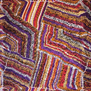 "Vibrant Aboriginal art quilting cotton fabric featuring the 'Mina Mina Dreaming' design by artist Polly Anne Napangardi Dixon. The intricate pattern displays a mosaic of colorful dots in shades of purple, red, orange, and yellow, forming textured geometric paths and ancestral tracks."
