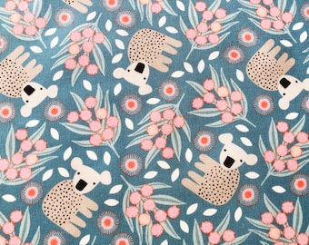 May include: A teal fabric with a repeating pattern of koalas, pink flowers, and white leaves. The koalas have dotted bodies and white faces with black eyes. The flowers are pink with orange centers, and the leaves are green.