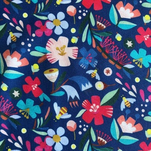 May include: A fabric with a vibrant floral design. The pattern includes red, pink, blue, and white flowers, green leaves, and yellow bees, all set against a dark blue backdrop. The design is densely packed and colourful.