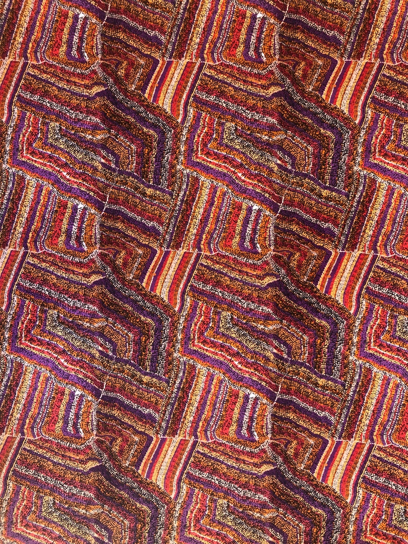 "Vibrant Aboriginal art quilting cotton fabric featuring the 'Mina Mina Dreaming' design by artist Polly Anne Napangardi Dixon. The intricate pattern displays a mosaic of colorful dots in shades of purple, red, orange, and yellow, forming textured geometric paths and ancestral tracks."
