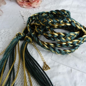 May include: A braided green and gold cord with tassels and gold charms. The cord is made of two different types of fabric, one green and one gold.
