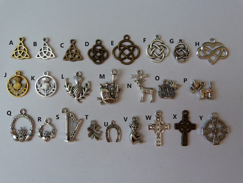 Peut inclure: Un ensemble de 26 breloques en argent et en bronze, chacune avec un design diff&eacute;rent. Les breloques comprennent des n&oelig;uds celtiques, des chardons, une harpe, un tr&egrave;fle, un fer &agrave; cheval, un cerf, un dragon, un chien, une croix et un c&oelig;ur. Les breloques sont dispos&eacute;es en ordre alphab&eacute;tique de A &agrave; Z.