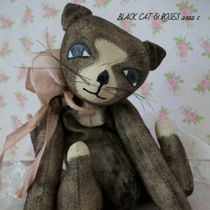 May include: A vintage black and white fabric cat doll with a pink ribbon and a white polka dot ball. The doll is sitting on a white lace surface. The text "Vintage Kitten & Ball" is printed below the doll.