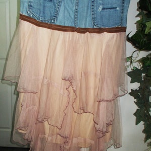 May include: A denim skirt with a brown belt and a layered tulle skirt in a light pink color.
