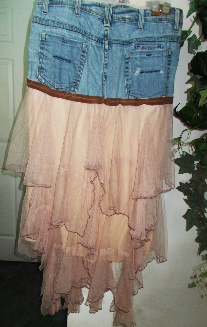May include: A denim skirt with a brown belt and a layered tulle skirt in a light pink color.
