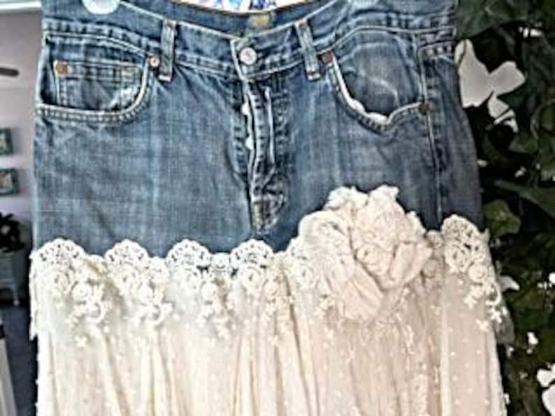 May include: A denim skirt with a light blue wash, featuring a white lace overlay at the hem. The skirt has classic five-pocket styling and a button-and-zipper closure. The lace adds a feminine touch to the casual denim.