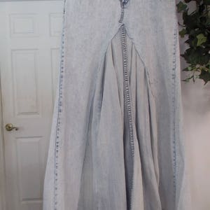 Puede incluir: Una falda maxi de mezclilla azul claro con una abertura frontal y un dise&ntilde;o plisado.